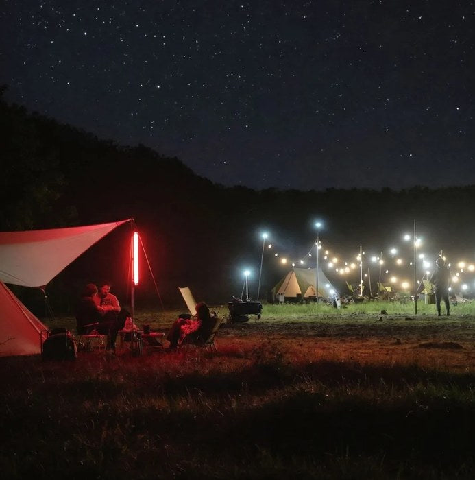 Acampada de noche con luz roja LumaAir Original bajo un cielo estrellado